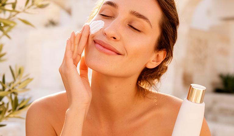 Donna in vacanza che protegge la pelle del viso all